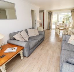 A living room with two grey sofas and a wooden coffee table next to a dining area with a table and chairs at Forbes C1 in Yarmouth