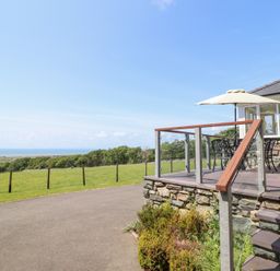 A patio area with furniture overlooking a field at Ysgubor Newydd Parc Isaf Dyffryn Ardudwy