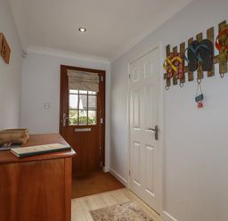 An entryway with a wooden door a chest of drawers a white door and flip flop wall decorations at 3 The Bowling Green in St Just in Roseland near St Mawes