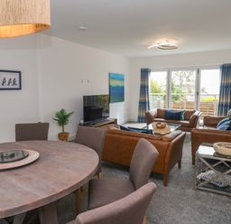 A living room with a sofa and dining area at Miramar in St. Ives