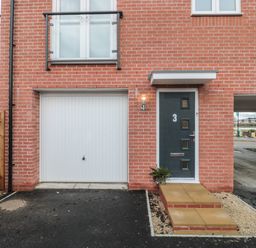 A front entrance with a dark door numbered 3 and a white garage door on a red brick house with a small porch and driveway at Cotswold Outlet Coach House in Tewkesbury