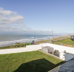 A coastal view with grassy yard and white wall near the sea at The Gables in Tywyn