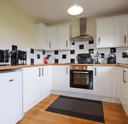 A kitchen with white cabinets a microwave oven and a kettle at Gwanda Tregolds near St Merryn