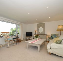 A living room with large window rocking chair and sofa with cushions at Trestar in Polzeath