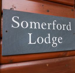 A name sign on wooden paneling that reads Somerford Lodge