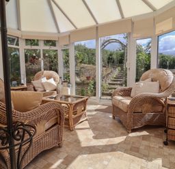 A conservatory with rattan chairs and a coffee table at Little Willesleigh in Goodleigh near Barnstaple