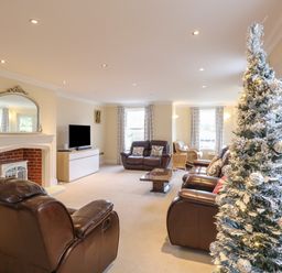 A living room with brown leather sofas a decorated Christmas tree and a fireplace at The Little House in Horning