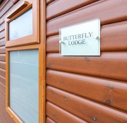 A wooden exterior wall with two frosted windows and a sign reading Butterfly Lodge at Butterfly Lodge in Tunstall near Catterick North Yorkshire