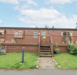 A cabin with a deck and steps at Butterfly Lodge in Tunstall near Catterick, North Yorkshire