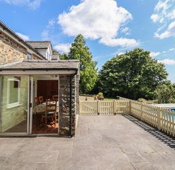 An outdoor area with a stone wall and dining table at Bryn Y Garreg Cottage - The Wireless Free Farm in Llangadfan near Llanwddyn