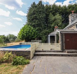 An outdoor area with a swimming pool and a stone house at Bryn Y Garreg Cottage - The Wireless Free Farm in Llangadfan near Llanwddyn