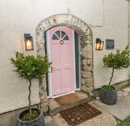 A pink door with stone arch and two plants in pots at Norchard Farm House Redberth near St Florence