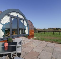 A patio with chairs and table outside a pod-shaped building at Leadon View Willow in Upleadon near Newent