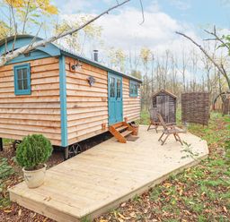 A wooden cabin with blue doors and windows on a wooden deck with chairs and a potted plant at Catchwater in Keal Cotes near East Kirkby