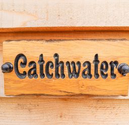 A wooden sign with the word Catchwater attached to a wooden surface