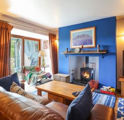 A living room with a wood burning stove and blue accent wall at Hendre in Blaenau Ffestiniog