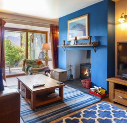 A living room with a blue accent wall fireplace wooden coffee table and television at Hendre in Blaenau Ffestiniog