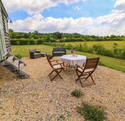 An outdoor seating area with a table and chairs at Goose Whistle Hut in Foxham