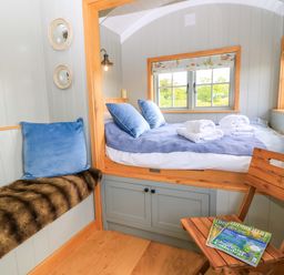 A bedroom with a bed and chair at Goose Whistle Hut in Foxham