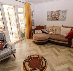 A living room with a round rug a sofa with cushions and a chair next to glass doors at Alban Road in Llanelli