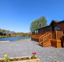An outdoor area with a lodge and deck near a river at Lakeside Lodge Bowland Lakes Leisure Village near Garstang