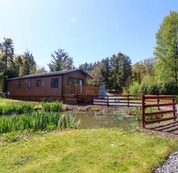 A lodge with a deck beside a pond at Lakeside Lodge Bowland Lakes Leisure Village near Garstang