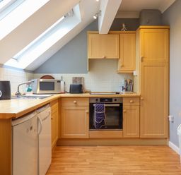 A kitchen with wooden cabinets a built-in oven a microwave a kettle and two skylight windows at 5 Lakeview Rise in Highampton near Hatherleigh