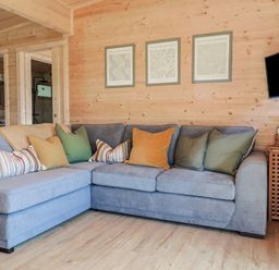 A living room with a grey sectional sofa and multiple cushions under three framed pictures at Foxglove in Higher Wambrook near Chard