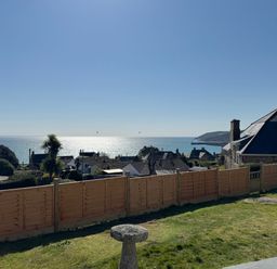 A garden with a wooden fence overlooking rooftops and the sea at Karenza in Penzance