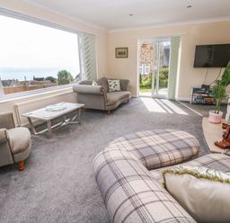 A living room with large windows and a sofa at Karenza in Penzance