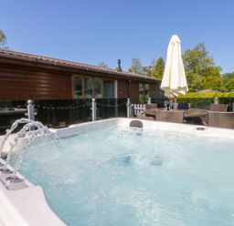 A hot tub with outdoor furniture and an umbrella at Dovedale Lodge in Troutbeck Bridge
