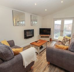 A living room with a coffee table and television at Dovedale Lodge in Bowness 70, White Cross Bay near Windermere