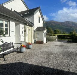 An outdoor view of a house with a bench and flower pots at Fox Howe in Thornthwaite