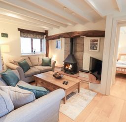 A living room with a fireplace and sofa at Jasmine Cottage in Thornthwaite