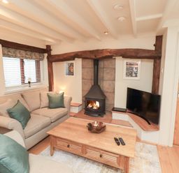A living room with a fireplace and sofa at Jasmine Cottage in Thornthwaite
