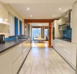 A kitchen with black countertops white cabinets and a dining area in the background at Tealby in Horning