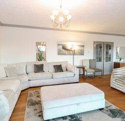 A living room with sofas chairs an ottoman a rug wall art and a chandelier at White Gables in Horning