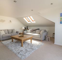 A living room with two sofas a wooden coffee table and skylight windows at Atlantic View in Holywell Bay