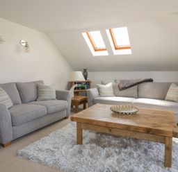 A living room with two gray sofas a wooden coffee table and skylight windows at Atlantic View in Holywell Bay