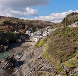 A coastal village with houses on a hillside and a rocky shoreline at Suntrap House in Portloe
