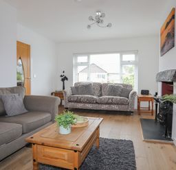A living room with two sofas a wooden coffee table and a fireplace at Monarfon in Criccieth
