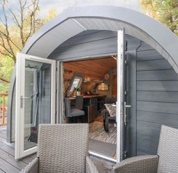 A small curved cabin entrance with open double doors showing a kitchen and seating area at Elleric Pods - The Last Resort Fasnacloich near Appin