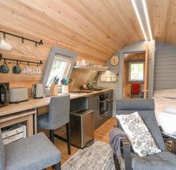 A compact living space with kitchen appliances chairs a bed and wood-paneled walls at Elleric Pods - The Last Resort in Fasnacloich near Appin