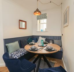 A dining room with a round table and seating at Weyside in Weymouth