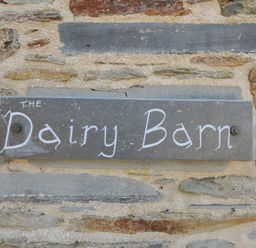 A sign for The Dairy Barn attached to a stone wall in Camelford