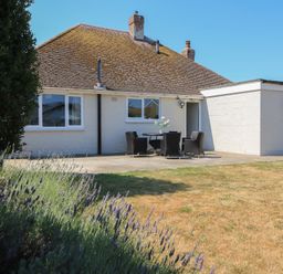 A house with a patio and chairs at Bayview Cottage in Southbourne