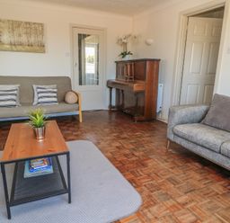 A living room with a piano and sofa at Bayview Cottage in Southbourne
