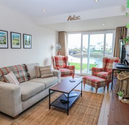 A living room with a sofa and armchairs overlooking a view at Oakley View Apartment in Porthmadog