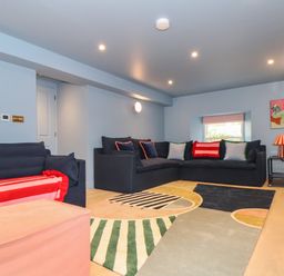 A living room with dark sofas a colorful rug and a red tiled fireplace at Mavericks Wave in St Agnes