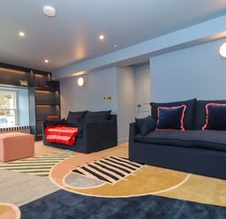 A living room with two navy sofas a colorful rug a pink ottoman and a window seat at Mavericks Wave in St Agnes